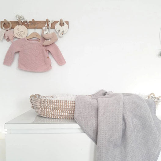 Weißes Babybett mit Schwanen-Mobile und grau-melierter Decke